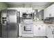 Kitchen with stainless steel refrigerator, white appliances and cabinets and green accent walls at 684 Rochester Ct, New Smyrna Beach, FL 32168