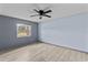 Bright bedroom featuring a ceiling fan, light wood floors, and a large window with neighborhood views at 800 Black Duck Dr, Port Orange, FL 32127