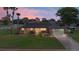 Inviting home exterior at dusk, featuring solar panels and a beautifully landscaped yard with mature palm trees at 800 Black Duck Dr, Port Orange, FL 32127