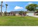 Charming brick home with a well-manicured lawn, palm trees, and solar panels on a sunny day at 800 Black Duck Dr, Port Orange, FL 32127