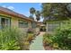 Charming exterior with a green walkway, tropical landscaping, leading to outdoor seating and adjacent building at 807 Craig St, New Smyrna Beach, FL 32168