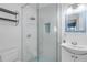 Bright bathroom featuring walk-in shower with blue and white tile, sink, and mirror at 821 Ocean Ave, New Smyrna Beach, FL 32169