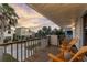 Relax on the covered wood balcony with chairs overlooking the street and palm trees at sunset at 895 Catfish Ave, New Smyrna Beach, FL 32169