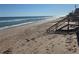 Stunning beach access with wooden steps to pristine sands and ocean views, offering a direct path to coastal bliss at 895 Catfish Ave, New Smyrna Beach, FL 32169