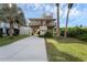 Coastal home on stilts with a driveway, grassy yard, lush landscaping, and wrap-around porch at 895 Catfish Ave, New Smyrna Beach, FL 32169