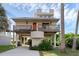 Charming two-story stilt home with a balcony, an orange door, and covered parking on a sunny day at 895 Catfish Ave, New Smyrna Beach, FL 32169