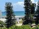 Charming beach home featuring a white exterior, and views of the ocean beyond tall pine trees at 895 Catfish Ave, New Smyrna Beach, FL 32169