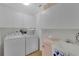 Organized laundry room with white cabinets, washer, dryer, sink, and unique pink refrigerator at 895 Catfish Ave, New Smyrna Beach, FL 32169