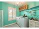 Laundry room features washer, dryer, sink, and storage with a pop of vibrant aqua color at 904 Clubhouse Blvd, New Smyrna Beach, FL 32168