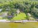 Aerial view of waterfront home featuring lush green lawn, a dock, a boat lift, and mature trees at 154 Godfrey Rd, Edgewater, FL 32141