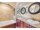Bathroom featuring double sinks, warm wood cabinets, framed mirrors, and a tiled shower and bath at 154 Godfrey Rd, Edgewater, FL 32141