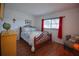 Comfortable bedroom boasts hardwood floors and a sun-filled window dressed with red curtains at 101 N Riverside Dr # 1090, New Smyrna Beach, FL 32168