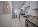 Galley kitchen featuring white cabinets, stainless appliances, granite counters, and tile flooring at 101 N Riverside Dr # 1090, New Smyrna Beach, FL 32168