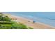 Panoramic view of the sandy beach, blue ocean, and coastal vegetation with people enjoying the seaside at 1051 Ocean Shore Blvd # 502, Ormond Beach, FL 32176