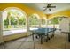 Covered outdoor patio featuring a ping pong table and arched openings to the backyard at 1212 S Riverside Dr, New Smyrna Beach, FL 32168