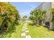 Expansive backyard showcasing a stone paver walkway leading to a refreshing pool area surrounded by tropical foliage at 1219 Commodore Dr, New Smyrna Beach, FL 32168
