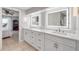 Bright bathroom featuring double vanity, backlit mirrors, and tiled floors; bedroom partially visible through door at 1219 Commodore Dr, New Smyrna Beach, FL 32168