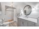 Bright bathroom featuring a gray vanity, modern fixtures, and a tiled shower with a decorative mirror at 1219 Commodore Dr, New Smyrna Beach, FL 32168