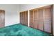 A bedroom with dated green carpets and and louvered door closets at 1219 Commodore Dr, New Smyrna Beach, FL 32168