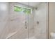 Shower featuring marble-look tile, glass surround, rain shower head and a small window providing ample natural light at 1219 Commodore Dr, New Smyrna Beach, FL 32168