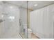 Shower with white tile, glass surround, and toilet; shower curtain on other side with white and gold pattern at 1219 Commodore Dr, New Smyrna Beach, FL 32168