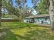 Home's exterior and patio surrounded by a lush green lawn and mature trees at 1331 Needle Palm Dr, Edgewater, FL 32132