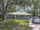 View of a single-story home with a well-maintained lawn, mature trees, and a paved driveway at 1331 Needle Palm Dr, Edgewater, FL 32132