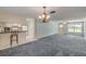 Open-concept living room featuring neutral paint, carpet, large windows, and a view into the kitchen with breakfast bar at 2416 Pine Tree Dr, Edgewater, FL 32141