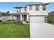 Two-story home featuring an attached two-car garage, well-maintained lawn, and front porch at 2667 Neverland Dr, New Smyrna Beach, FL 32168