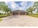 Spacious three-car garage with a paver driveway surrounded by lush landscaping and palm trees at 2939 Bella Flore Ter, New Smyrna Beach, FL 32168