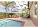 Gorgeous screened-in pool area with dining set, lounge chairs, and lush landscaping at 2939 Bella Flore Ter, New Smyrna Beach, FL 32168