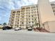 Beige condo building featuring multiple balconies, ample parking, and convenient ramp access to the entrance at 30 Inlet Harbor Rd # 606, Ponce Inlet, FL 32127