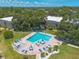 Aerial view of community pool with lounge chairs, tables, umbrellas, and clubhouse at 3800 Saxon Dr # 180, New Smyrna Beach, FL 32169