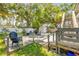Spacious backyard featuring grill, outdoor seating, shed, stairs, mature trees, and fence at 402 N Orange St, New Smyrna Beach, FL 32168