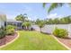 Well-manicured backyard featuring a brick border, green lawn, mature trees, and privacy fence at 406 Phillips Creek Ln, New Smyrna Beach, FL 32168