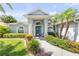 Charming home entrance with blue door, rocking chairs, and lush, colorful landscaping in a well maintained yard at 406 Phillips Creek Ln, New Smyrna Beach, FL 32168