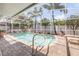 Screened-in pool area surrounded by a brick patio and palm trees, creating a backyard oasis at 406 Phillips Creek Ln, New Smyrna Beach, FL 32168
