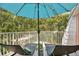 Outdoor deck with an umbrella, two lawn chairs, and wooded views at 4150 S Atlantic Ave # 111B, New Smyrna Beach, FL 32169