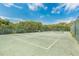 Outdoor tennis court surrounded by trees and a fence provides an area for recreational activities at 4150 S Atlantic Ave # 111B, New Smyrna Beach, FL 32169