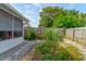 View of the backyard with a garden, gravel walkway, wooden fence and screened in patio at 5146 Pineland Ave, Port Orange, FL 32127