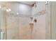 Shower featuring neutral-toned tile work with decorative accents and convenient corner shelves at 5207 S Atlantic Ave # 224, New Smyrna Beach, FL 32169