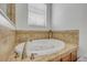 Luxurious soaking tub surrounded by decorative tile and natural light at 5849 Ansley Way, Mount Dora, FL 32757