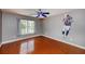 Bedroom featuring hardwood floors, ceiling fan, a window, and a unique wall decoration at 6065 Spruce Point Cir, Port Orange, FL 32128