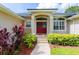 Close-up of the home's inviting red double-door entrance with lush landscaping and abundant sunlight at 6065 Spruce Point Cir, Port Orange, FL 32128
