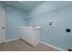 Bright laundry room with shelving, sink, and blue accent wall at 6065 Spruce Point Cir, Port Orange, FL 32128