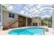Backyard pool area with a screened enclosure, wooden deck and stairs, and a view of the two-story home at 6065 Spruce Point Cir, Port Orange, FL 32128
