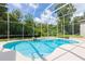 Inviting screened-in pool area with lush greenery and a unique rock feature, perfect for relaxation and enjoying the outdoors at 6065 Spruce Point Cir, Port Orange, FL 32128