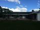 Back exterior view with patio and mature trees at 4500 S Hiawassee Rd, Orlando, FL 32835