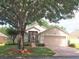 Charming home featuring a lush green lawn, mature trees, and a brick driveway leading to a two-car garage at 3918 Doune Way, Clermont, FL 34711