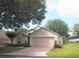 Charming single-story home with a well-maintained lawn, mature trees, and a brick driveway leading to a two-car garage at 3918 Doune Way, Clermont, FL 34711